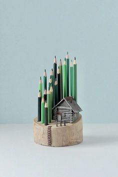 a group of green and white pencils sitting on top of a wooden holder with a house