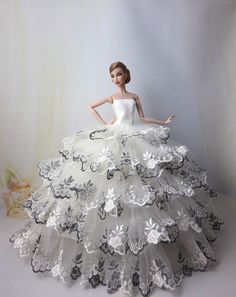 a barbie doll wearing a white dress with black and silver flowers on it's skirt