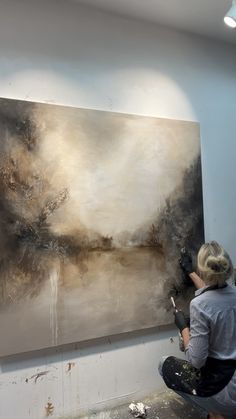 a woman is painting on the wall in an art studio