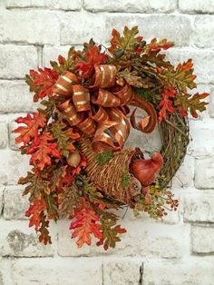 a wreath on a brick wall decorated with autumn leaves and other foliage, including an acorn