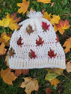 The perfect hat for fall! Made from 100% acrylic yarn, it features a cream base and a color changing leaf around the hat (leaf colors will vary). White Acrylic Hat For Fall, Fall Acrylic Beanie Cap, Fall Acrylic Beanie Hat, Crochet Hats For Fall, One Size, Crochet Hat For Fall, Handmade Fall Hats One Size, Crochet Fall Hat One Size, Handmade One Size Hats For Fall, Fall Acrylic Beanie One Size Fits Most