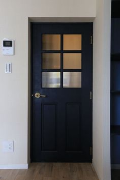 an empty room with a black door and wooden flooring on the side walk way