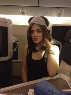 a woman sitting in an airplane with her hand on her head and looking at the camera