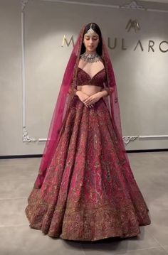 a woman in a red and gold bridal gown standing next to a sign that says mulbro