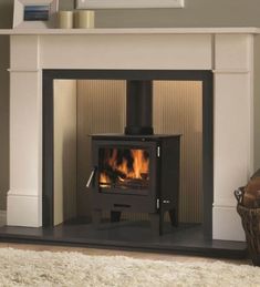 a fireplace with a wood burning stove in the center and a rug on the floor next to it