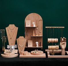 several wooden jewelry pieces on display in front of a dark green wall with white trim