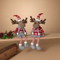 two stuffed reindeers are sitting on a shelf next to some christmas decorations and a tree branch