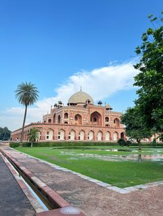 an old building in the middle of a park with palm trees and green lawns