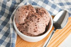 a bowl filled with ice cream on top of a wooden cutting board next to a spoon