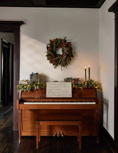 a christmas wreath hangs on the wall above a piano