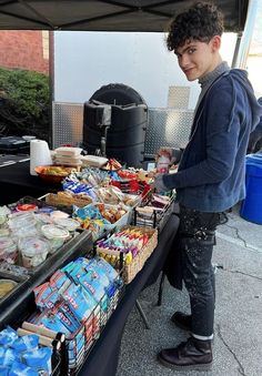 a young man standing next to a table filled with food