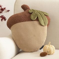 a stuffed acorn sitting on top of a white couch next to a knitted acorn