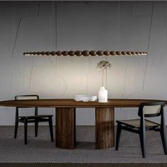 a dining table with two chairs and a vase on the top, in front of a white paneled wall