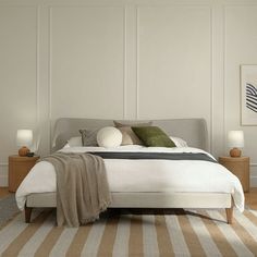 a large bed sitting on top of a wooden floor next to two nightstands with lamps