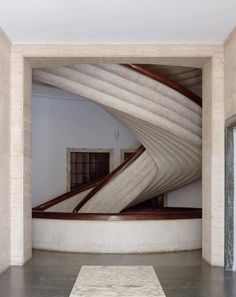 a room with a rug on the floor and an artistic staircase in the middle,