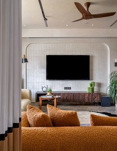 a living room with orange couches and a flat screen tv mounted on the wall