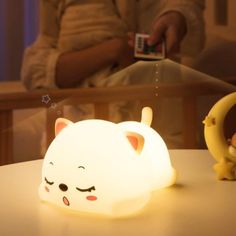 a white cat lamp sitting on top of a table next to a small figurine