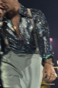 the man is singing into his microphone while holding something in one hand and wearing a jacket with sequins on it