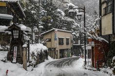 a snow covered street with buildings and trees on both sides in front of the road