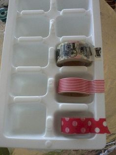 an ice tray with tape, money and other items in it sitting on a table