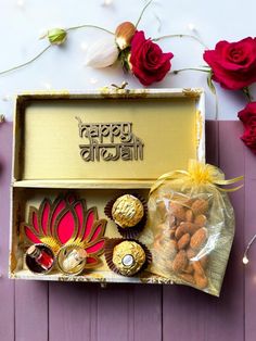 a box filled with assorted chocolates next to red roses and flowers on a table