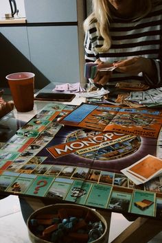 a woman sitting at a table with monopoly cards on it