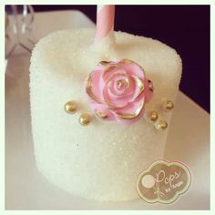 there is a cake with a pink rose on it and gold beads around the top