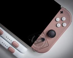 a pink nintendo wii game controller sitting on top of a white table next to a black screen