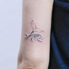 a woman's arm with a tattoo on it that has a whale tail in the water