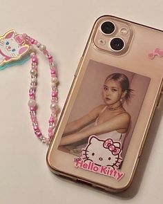 an iphone case with a hello kitty photo on it and a beaded necklace next to it