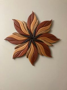 a decorative wall hanging made out of wood with leaves on the top and bottom part