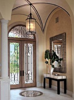 an entry way with arched glass doors and a mirror on the wall, along with a marble floor