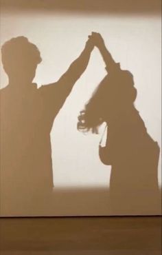 two people standing in front of a wall with their hands up to each other's head