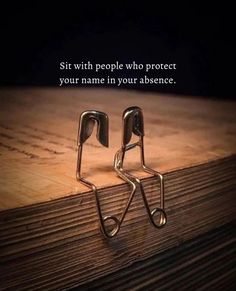 two pairs of scissors sitting on top of a wooden table next to a quote that reads sit with people who protect your name in your presence