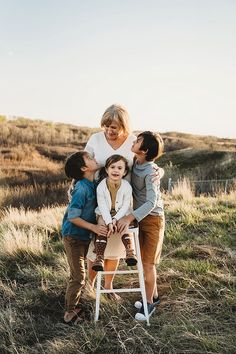 a woman and three children are sitting on a chair in the middle of a field