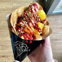 a person holding up a waffle with fruit and nuts on it in front of a wooden floor