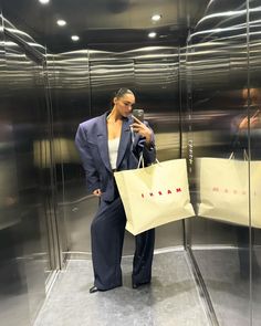 a woman holding a shopping bag and looking at her cell phone in an elevator area