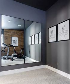 an exercise room with mirrors on the wall and pictures hanging on the wall behind it