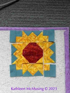 a close up of a piece of fabric with a sunflower on it and the words, kahlhen mc musing q 2013