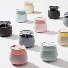 many different colored jars are arranged in a circle on a white surface, with the lids slightly open