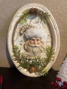 a plate with a santa clause on it next to a christmas tree and pine cones