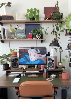 a desk with a computer, speakers and plants on the shelves above it is also a chair