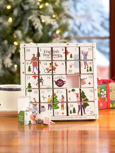 a wooden table topped with boxes filled with christmas decorations and gifts next to a christmas tree