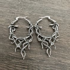 Add some edge to your look with our stunning Snake hoop earrings. With a unique snake design, these large hoop earrings exude a gothic feel. Make a statement and elevate your style with these bold earrings. Sold as Pair Material: 316 Stainless steel Size of the hoop : 63mm long, 38mm wide Standard Post 21G Listing for pair of hoops only *RETURNS / REFUNDS * -If you would like to return you purchase , please contact us within 7 days of receiving your package and we will accept the return.Return will only be made to the product, and not the shipping cost.  -Buyer is  responsible for the return shipping costs . -All jewelry must be returned unworn and in their original condition . *LOST MAIL* Once the package is marked as DELIVERED by the post office, we are not responsible for misplaced or s Handmade Edgy Metal Hoop Earrings, Handmade Gothic Hoop Jewelry, Wrapped Hoop Earrings, Earrings Snake, Largest Snake, Gothic Earrings, Wardrobe Accessories, Snake Jewelry, Bold Earrings