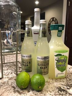 three bottles and two limes sitting on a counter