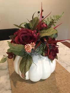 a white pumpkin filled with flowers on top of a table