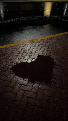 a heart shaped puddle on the ground in front of a building at night with lights reflecting off it