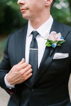 a man in a black suit with a flower on his lapel