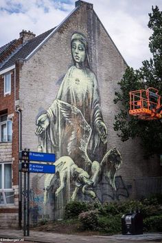 a large mural on the side of a building with a woman and two dogs next to it