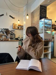 a woman sitting at a table with an open book